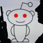 An image of a woman holding a cell phone in front of the Reddit logo displayed on a computer screen, on April 29, 2024, in Edmonton, Canada.