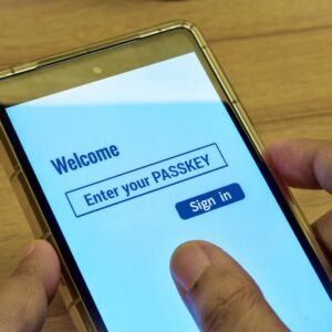 Woman using her phone with the digital display message enter your PASSKEY. Sign in page, modern technology, passwordless login method.