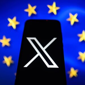 In this photo illustration an X logo is displayed on a smartphone with the European Union flag in the background.