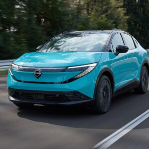 An electric blue Nissan Leaf drives towards the camera